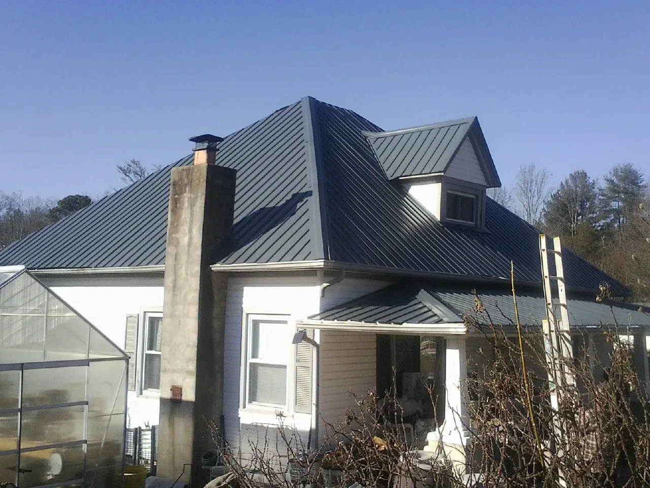 Dark blue standing seam metal roof on a white farmhouse with dormer — Slate & Tile Roof Repair by Roofing Brothers in Campbell