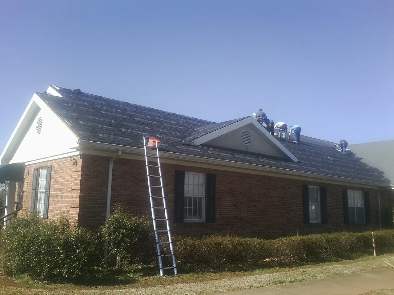 Crew tearing shingles off a brick ranch roof with a ladder set — Metal Roof Repair work by our crew in Campbell