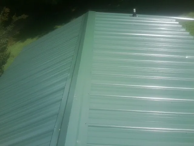 New green metal panels meeting at the ridge of a roof — Flat Roof Repair work by our crew in Campbell