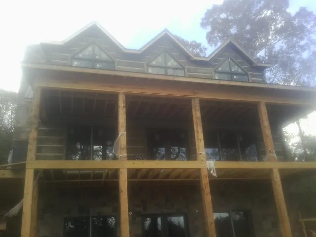 Dormers and porch framing on a large log home under construction — Roof Coating work by our crew in Campbell