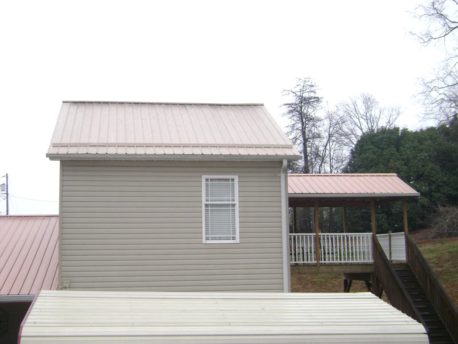 Tan metal roofs on a two story addition and attached porch, from a Roof Replacement job in Campbell