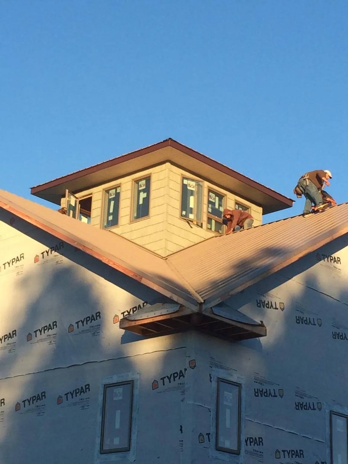 Roofers working around a rooftop cupola on a new metal roof at sunset — Roof Waterproofing in Campbell by Roofing Brothers